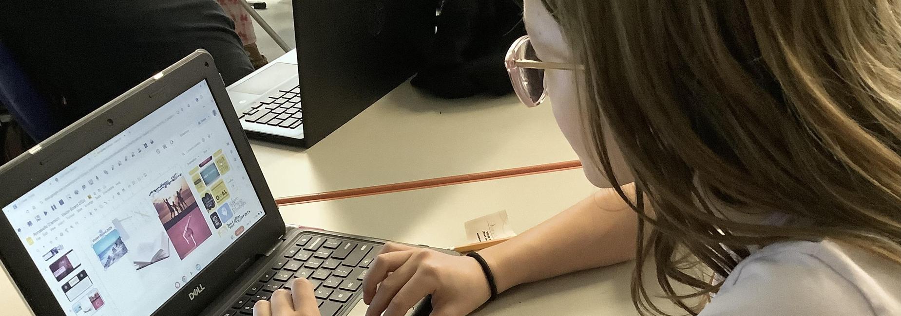 A student types on a laptop while viewing colorful digital content on the screen.