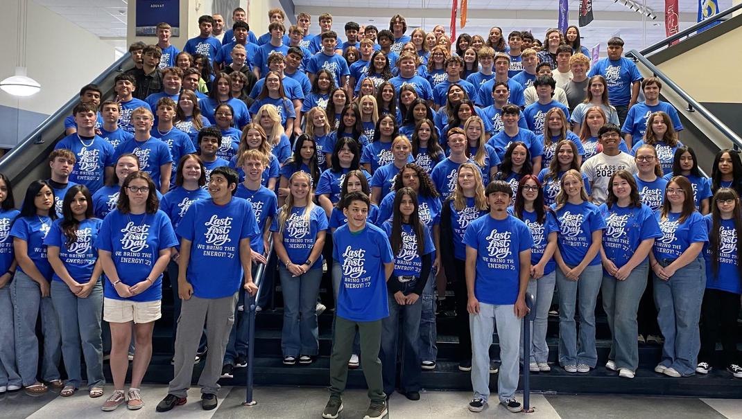 Large group of students in blue shirts gathered on staircase.