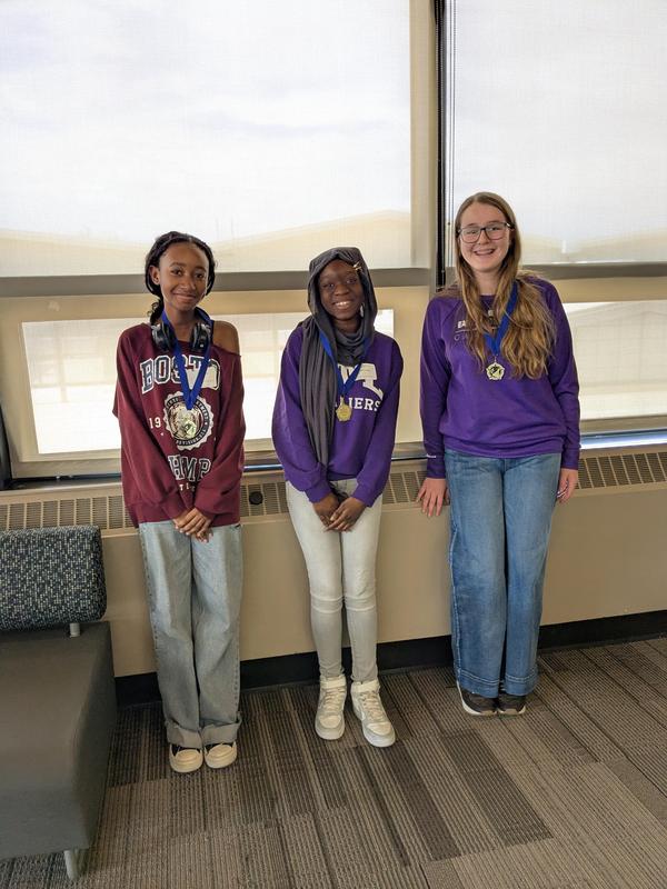 3 students standing in front of a window