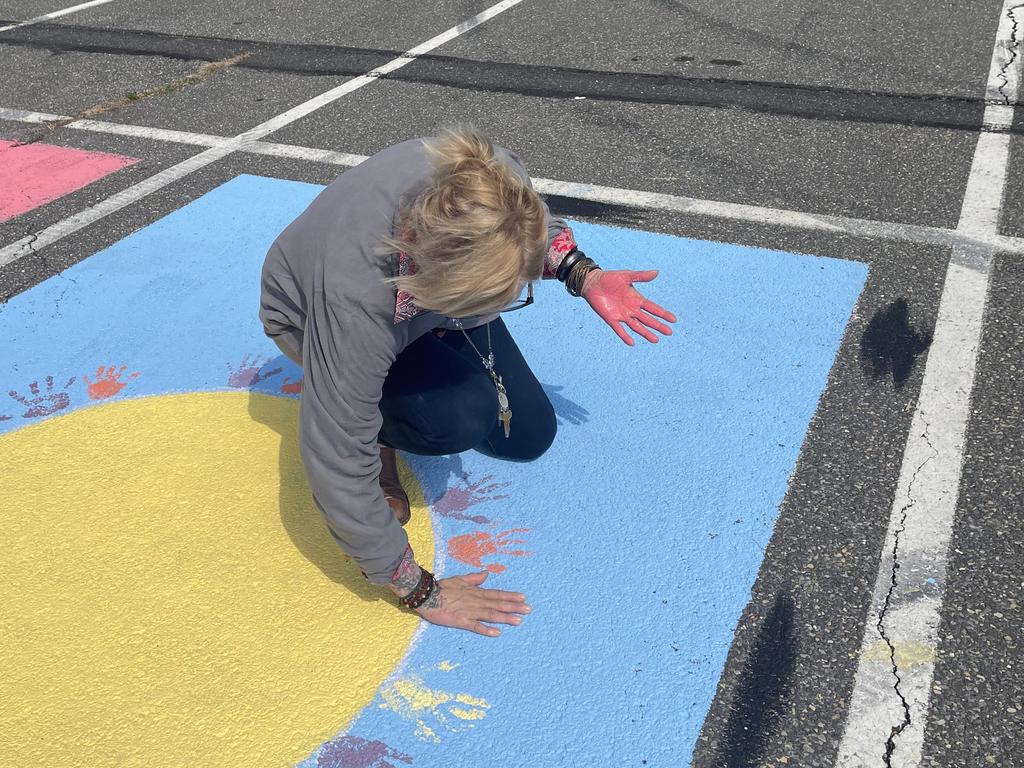 Person making a hand print in paint in a senior parking spot.