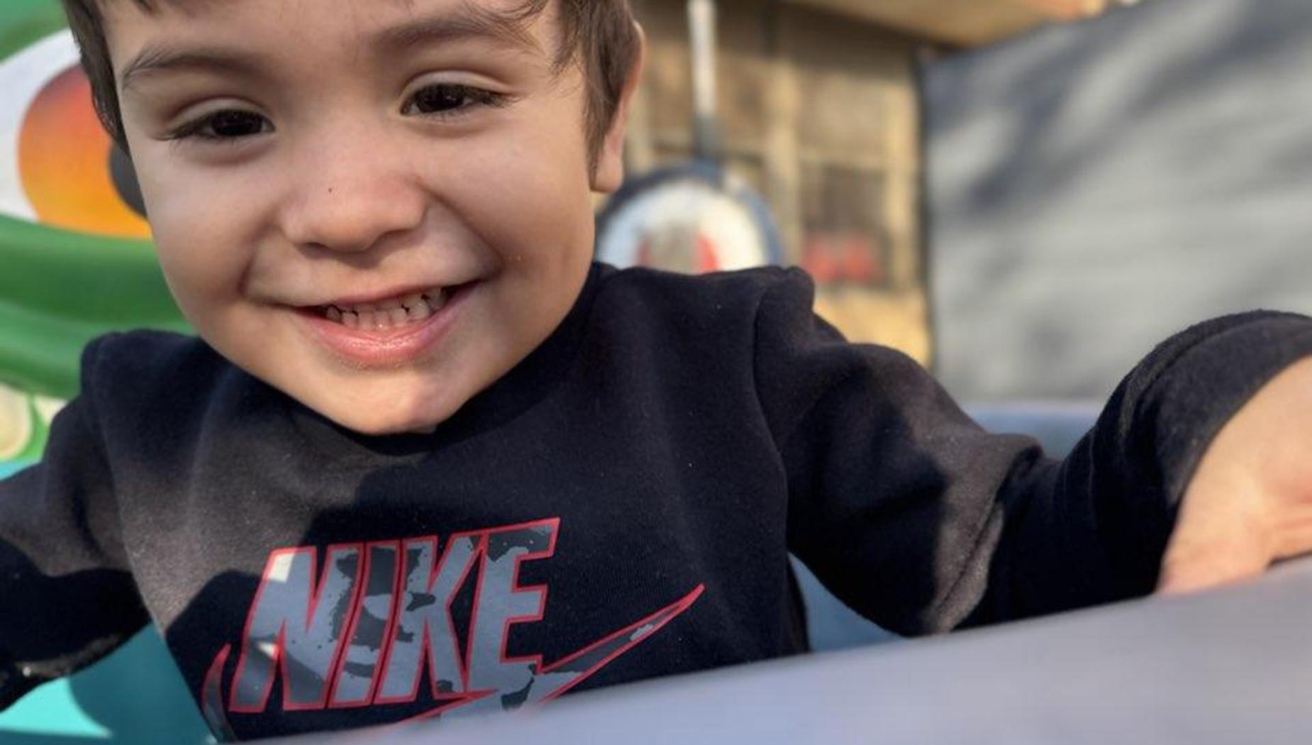 Smiling boy wearing a Nike shirt, playing in a colorful outdoor setting.