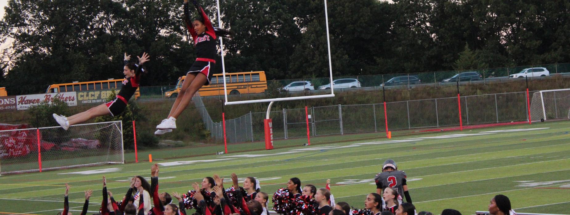 CHSW cheerleaders reaching up to catch two cheerleaders in the air while the rest look on.