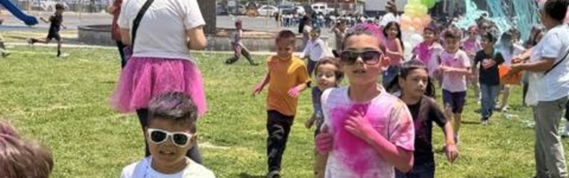 Group of children running on grass, wearing sunglasses and colorful shirts.