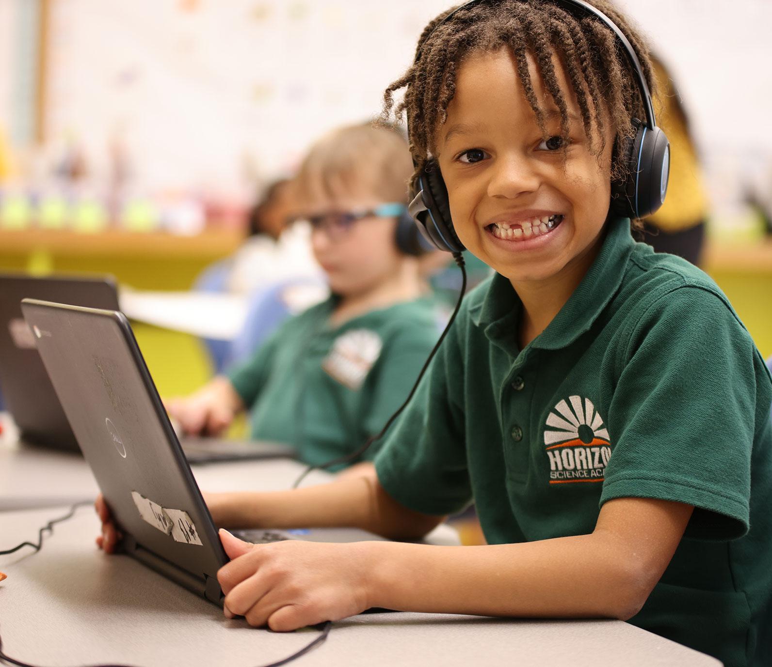 HSA St. Paul student wearing headphones uses a laptop in class