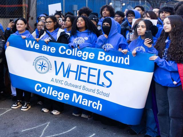Students holding a banner at a college march, showing excitement and support.