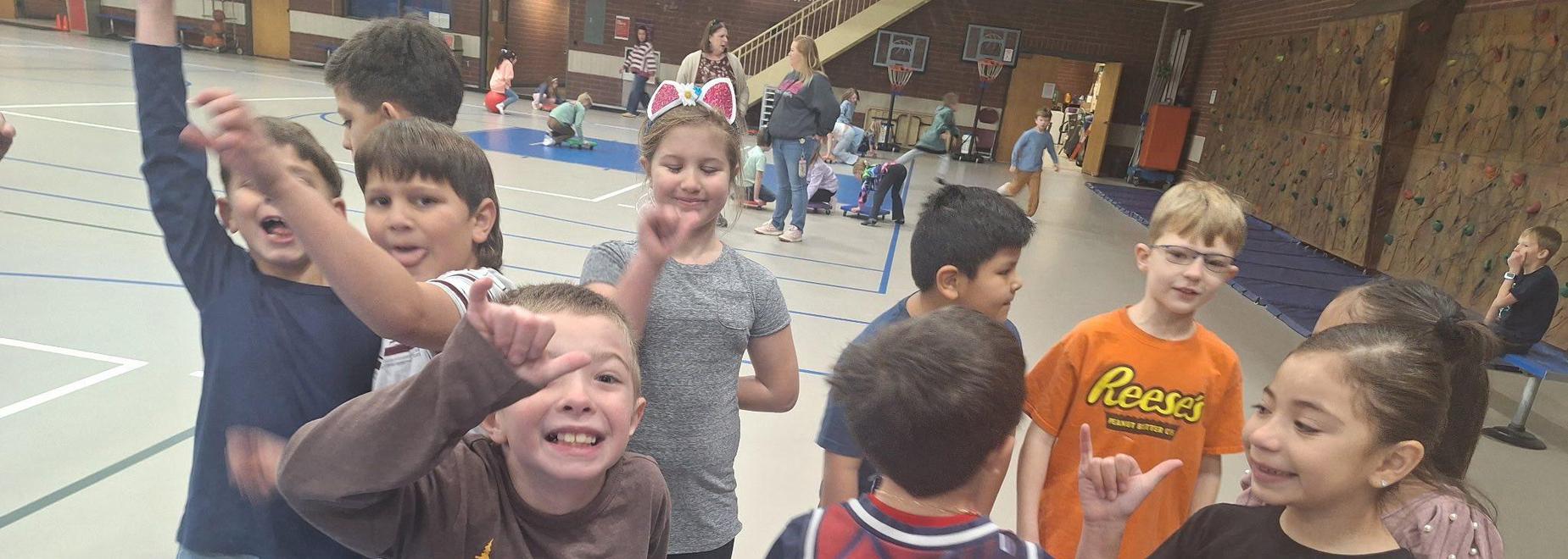 Group of children smiling and posing energetically in a gymnasium.