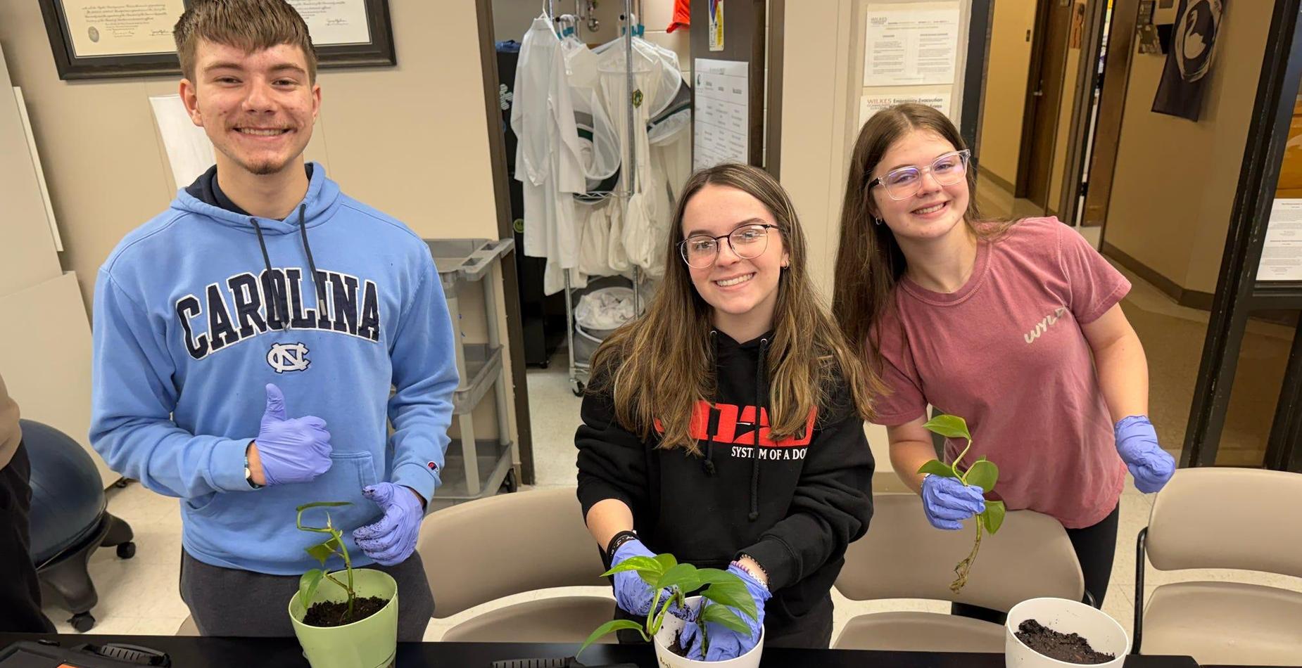 Three students smiling and holding potted plants in Dr. Pipes' Hort class