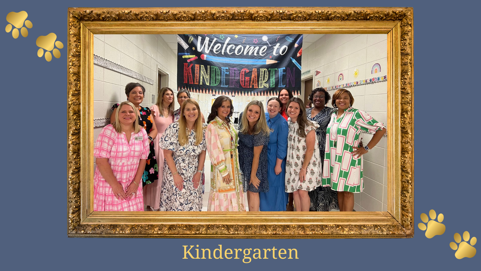Kindergarten teachers smiling together under a colorful welcome banner.