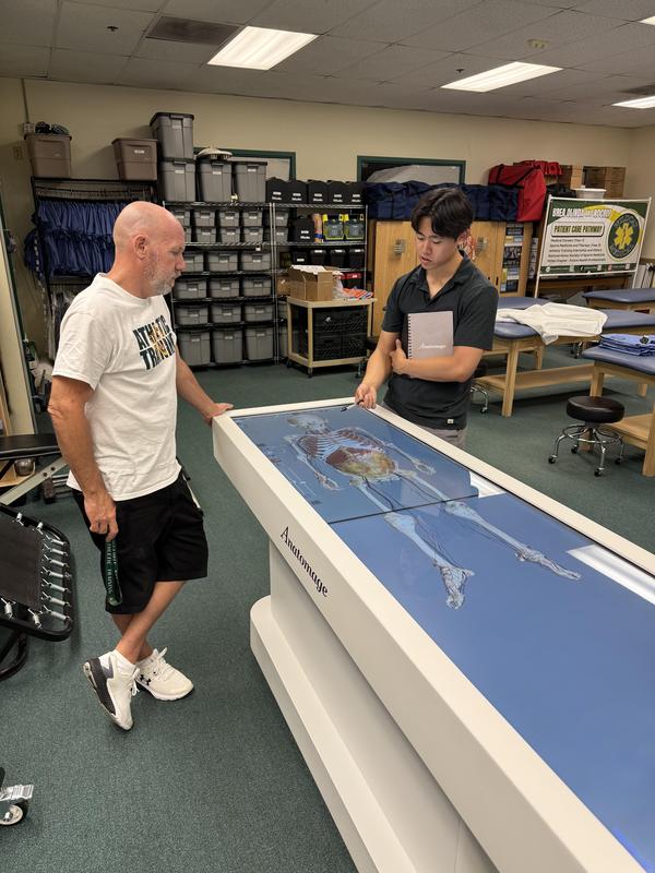 Instructor and student stand on each side of the Anatomage Table