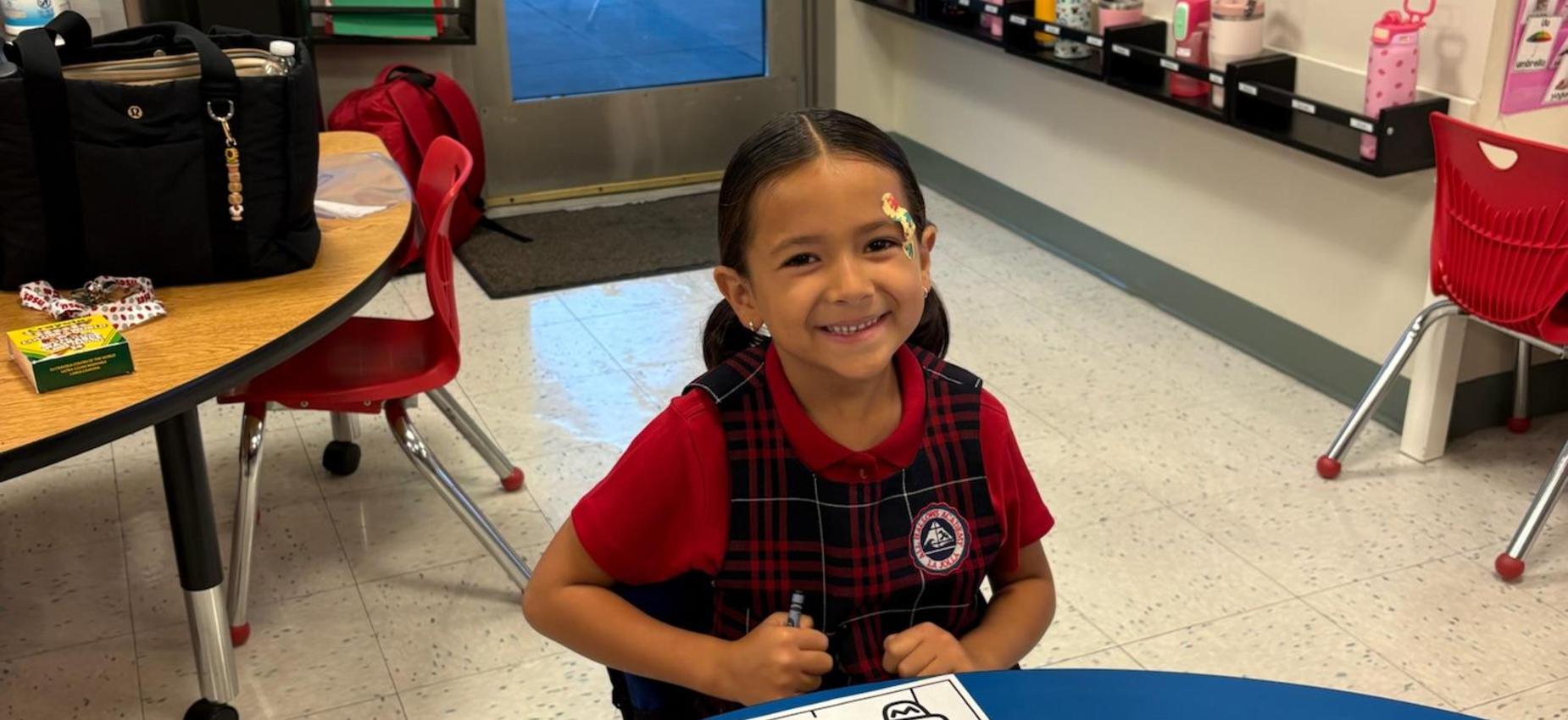 Kindergarten student sitting at des working for first day of school