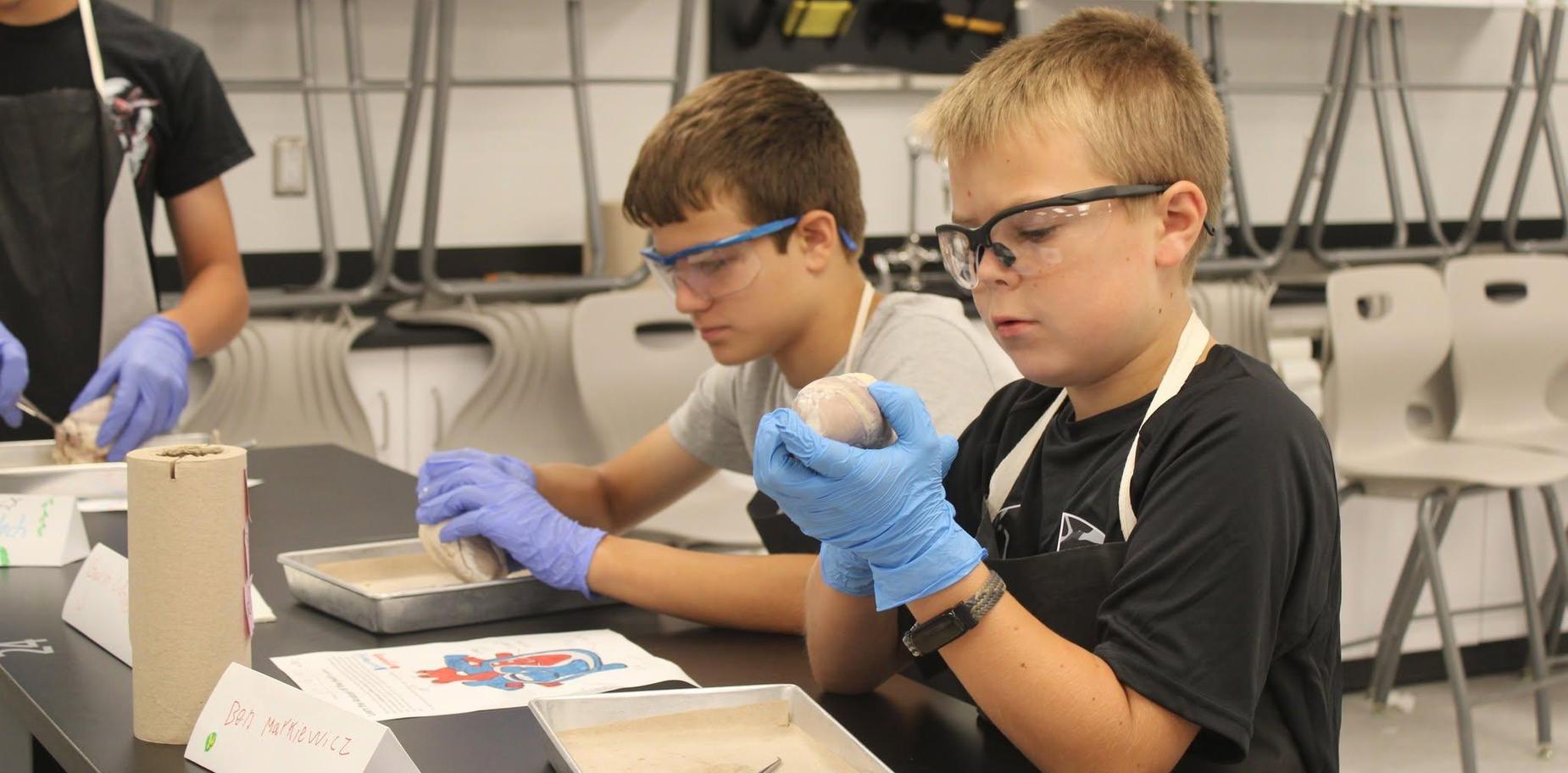 Two boys observing and working with materials in a science class.