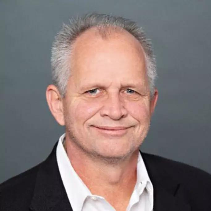 Older man with greying hair and a slight smile