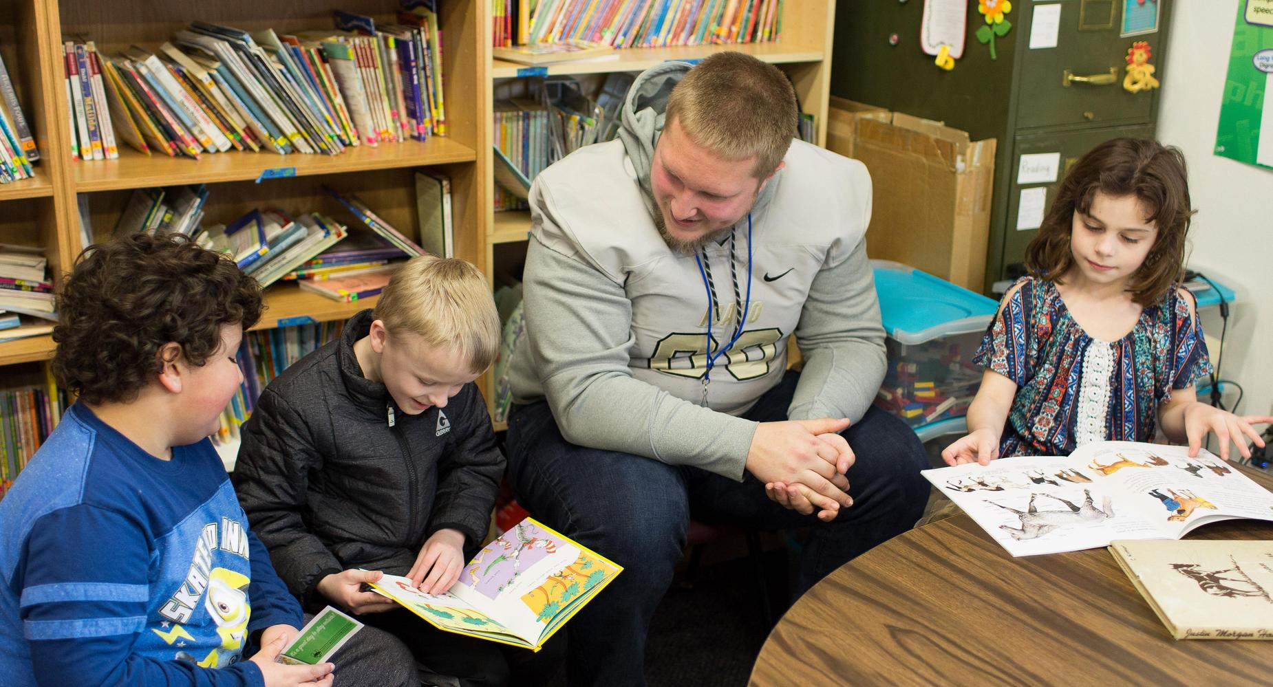 Vandal Football player reading to 2nd Graders