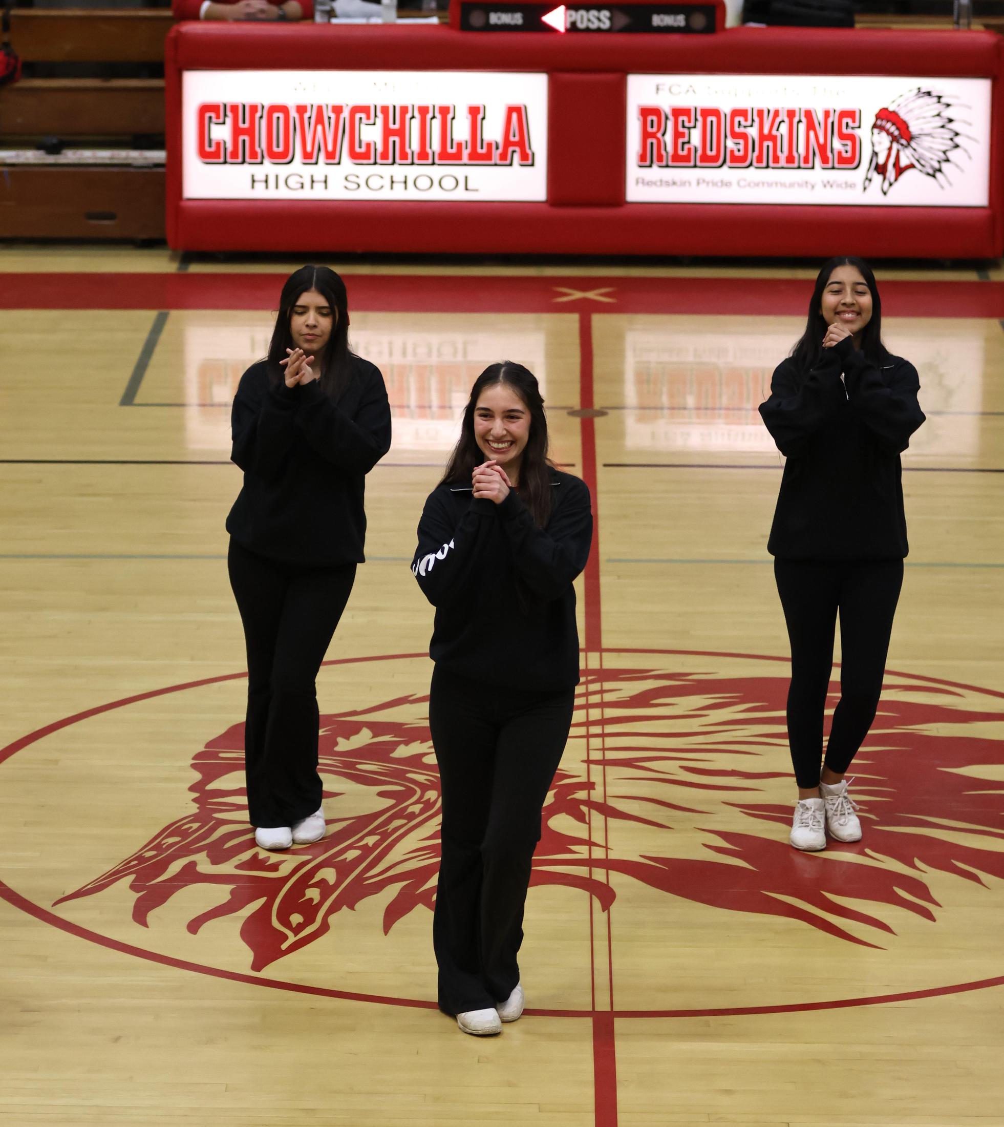 Varsity girls cheering at a basketball game against Mariposa