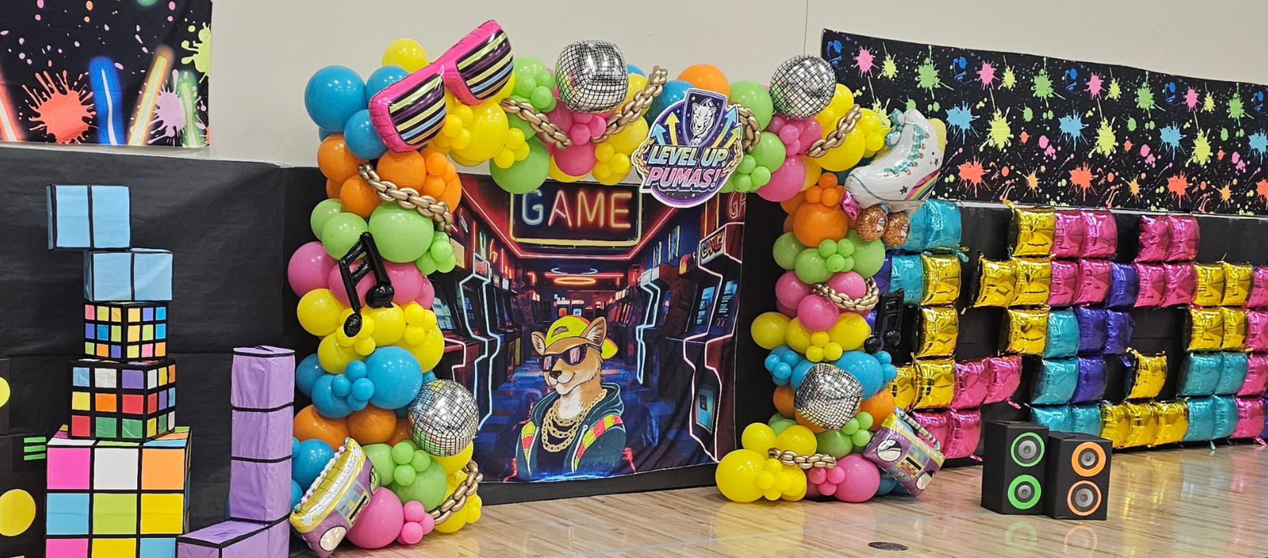 A vibrant decorative archway made of balloons and disco-themed elements for a game event.