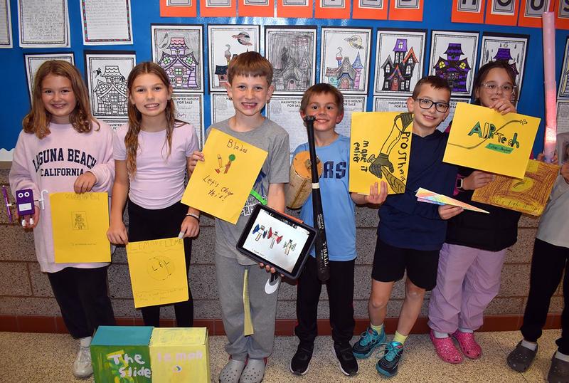 Six fourth-graders holding their inventions