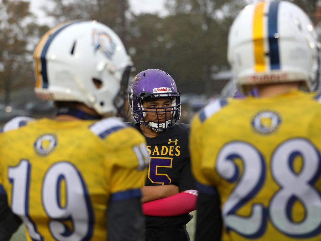 A Palisades Pirate football standing on the field between two opponents.