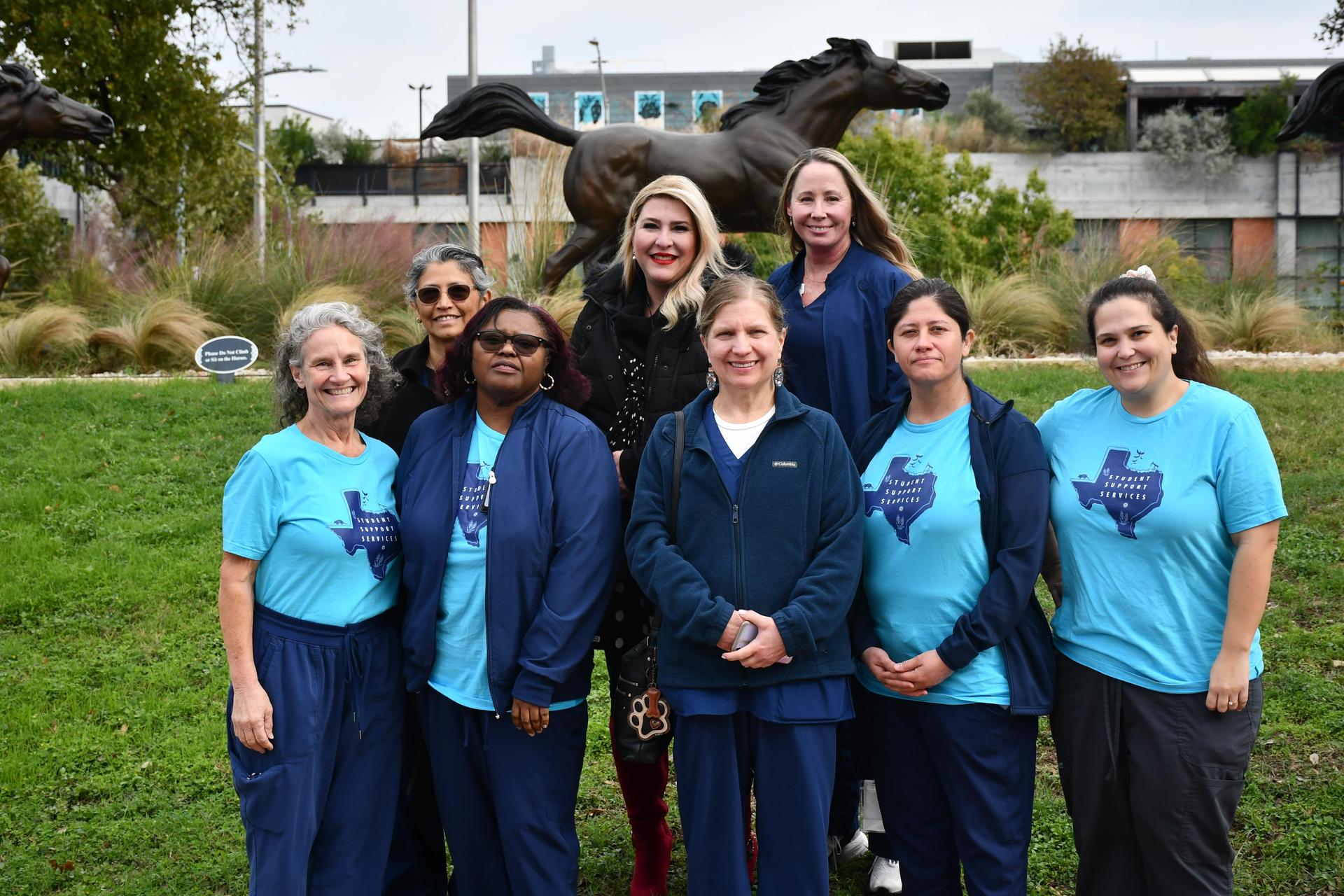 8 people standing behind the horse statues.