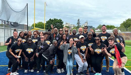 Large group of people in matching shirts posing for a photo at an outdoor event.