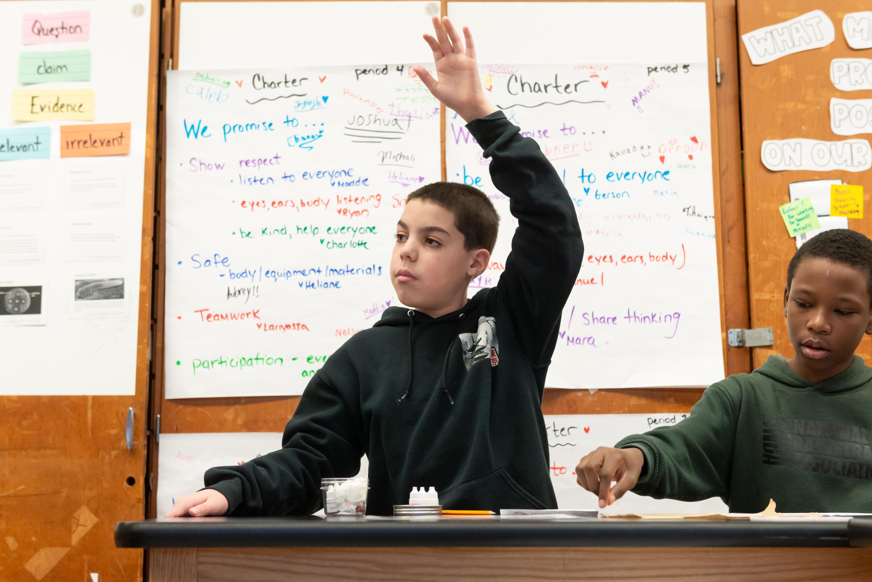 Student raising their hand while seated in class.