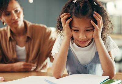 Student struggles with homework while a parent looks on