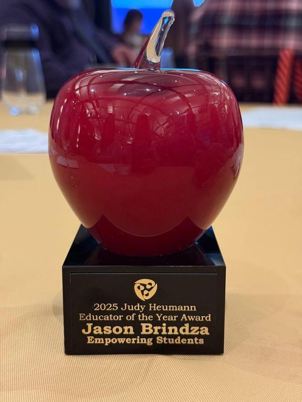 Image is of an award given to Mr. Brindza. It is a glass apple which says "Judy Heumann Educator of the Year Award"