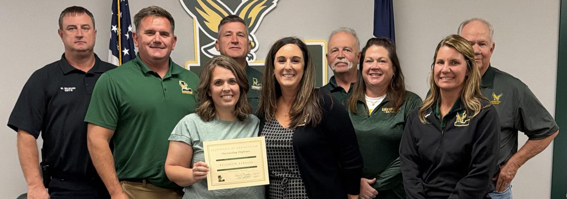 Group of people posing for a photo with a certificate presentation.