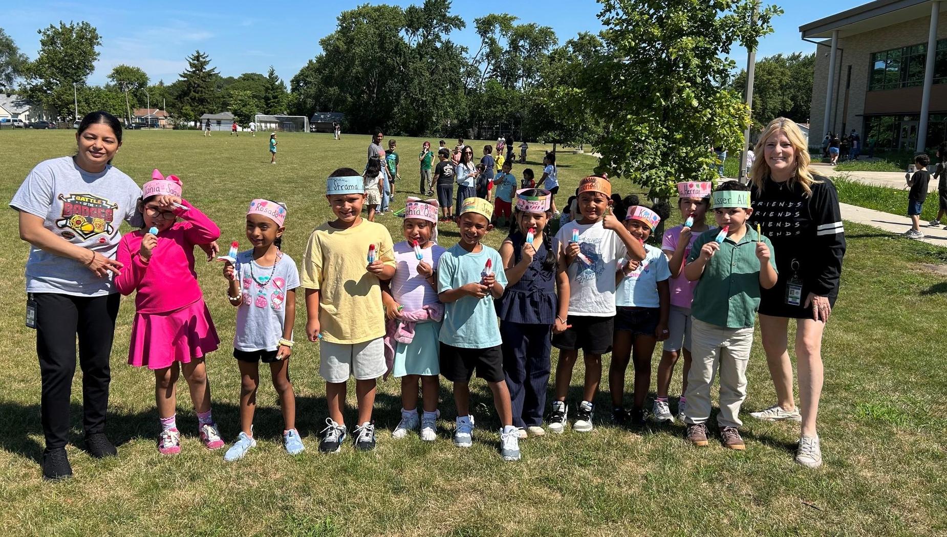 Group of children with ice pops posing in a park during a sunny day.