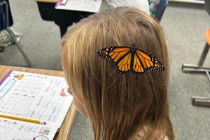 Lydia Mellon sits very still so she doesn’t disturb the butterfly on her head