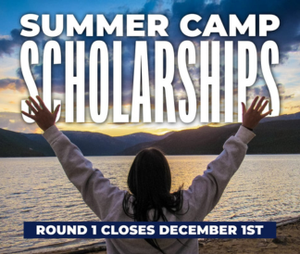 Summer Camp Scholarships with person standing in front of lake with arms raised