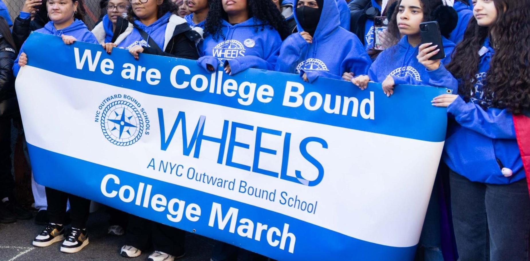 Group of students holding a banner that reads 'We are College Bound WHEELS'.