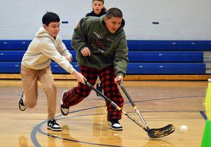 Two students running with hockey sticks in their hands