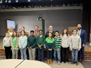 children wearing green and blue standing in front of adults smiling