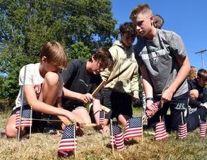 Students placing miniature flags in the ground during a memorial project.