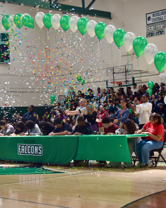 Confetti falls over students as they sing their letters committing to a college