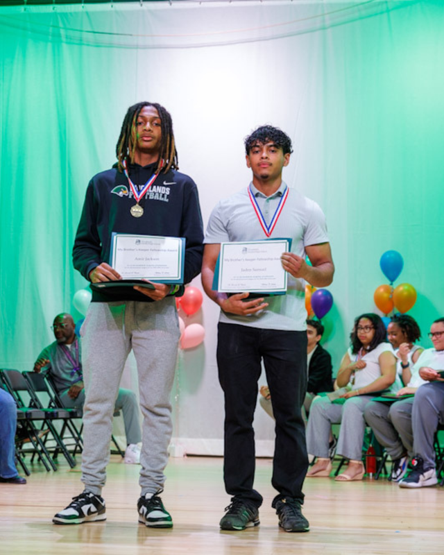 Two young men pose with certificates