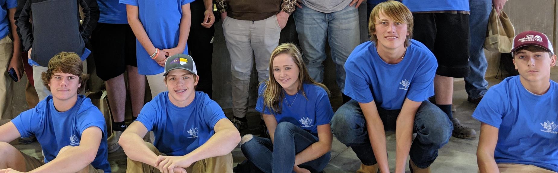 students in blue shirts smiling