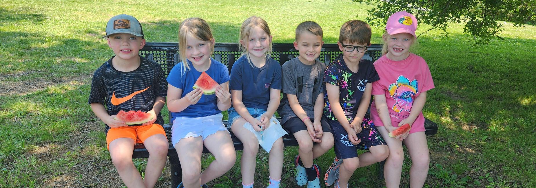 First Graders eat watermelon outside as part of their camping unit.