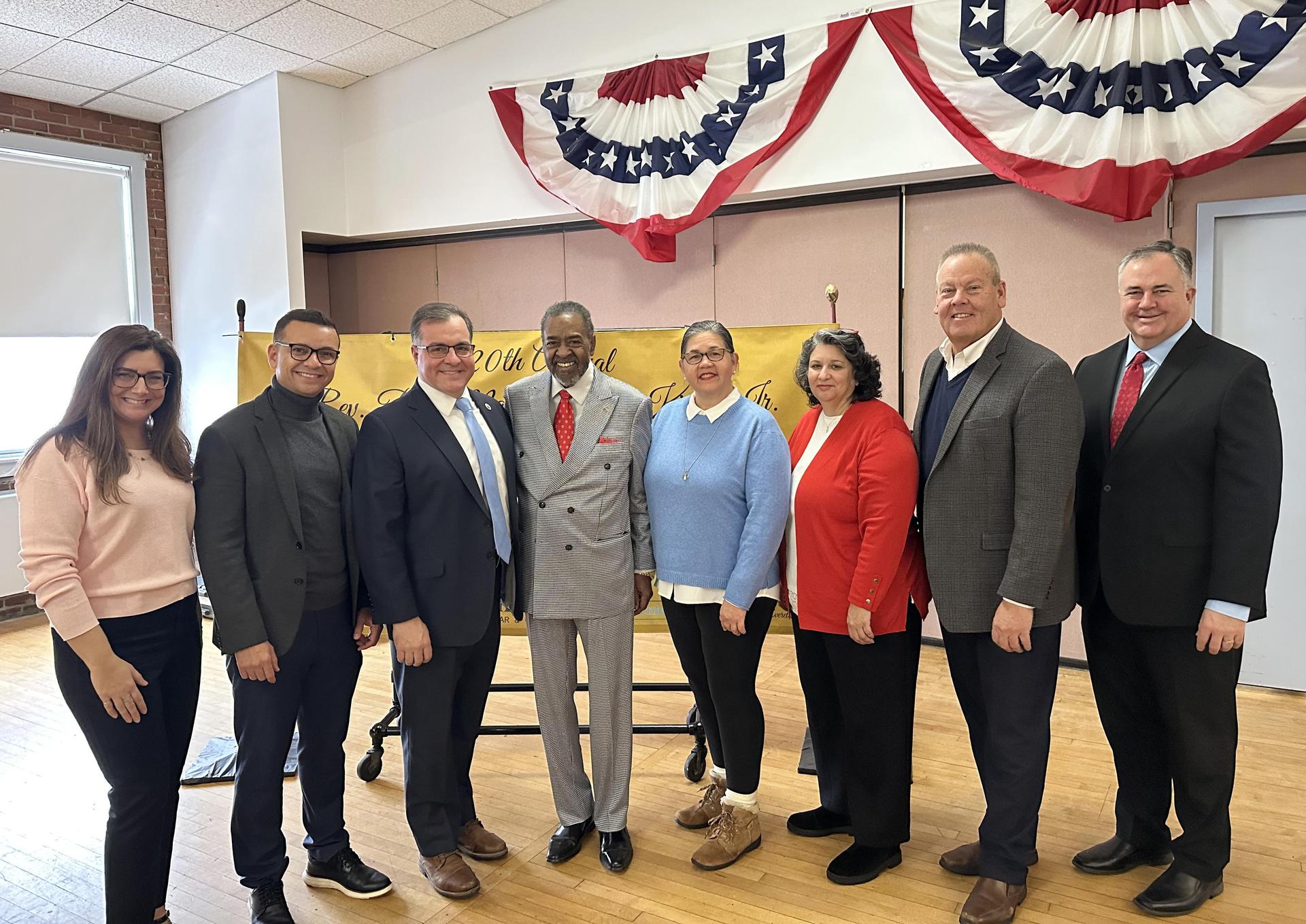 Politicians and community members gathered for a celebration in a decorated room.