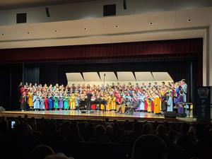 large choir on stage dressed in multi-colored choir robes