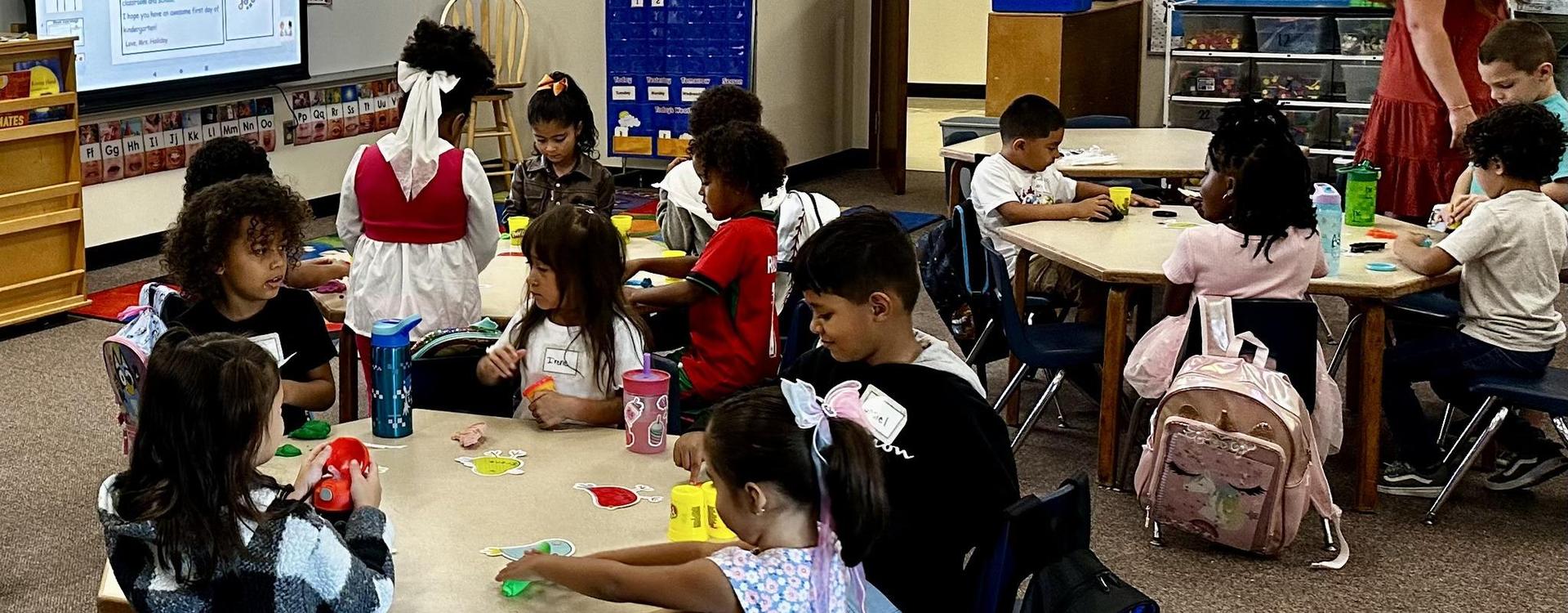 Children engaged in creative activities at a classroom table.