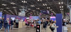 Busy convention hall filled with people and various booths.