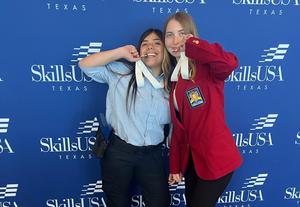 Two FHS skills students posting and biting their state medals