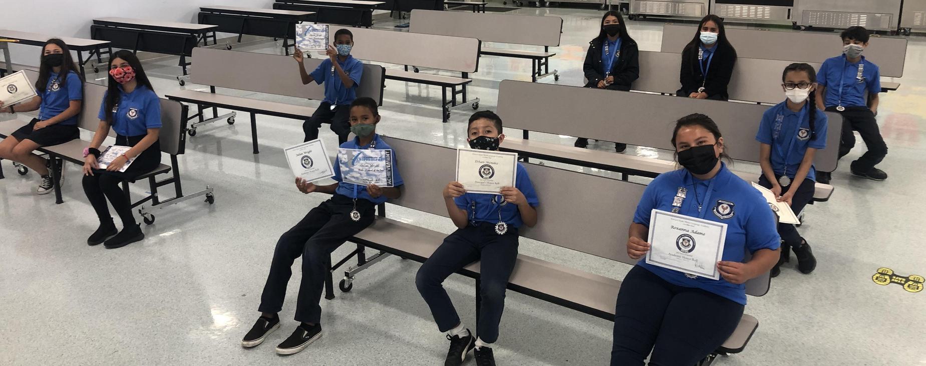 students sitting displaying certificates