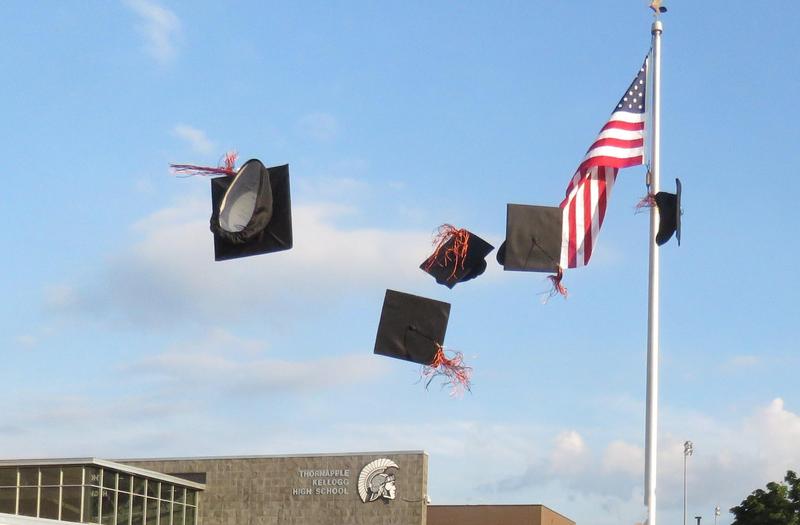 Graduation caps are tossed in the air.