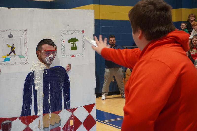 student throwing pie in face of teacher