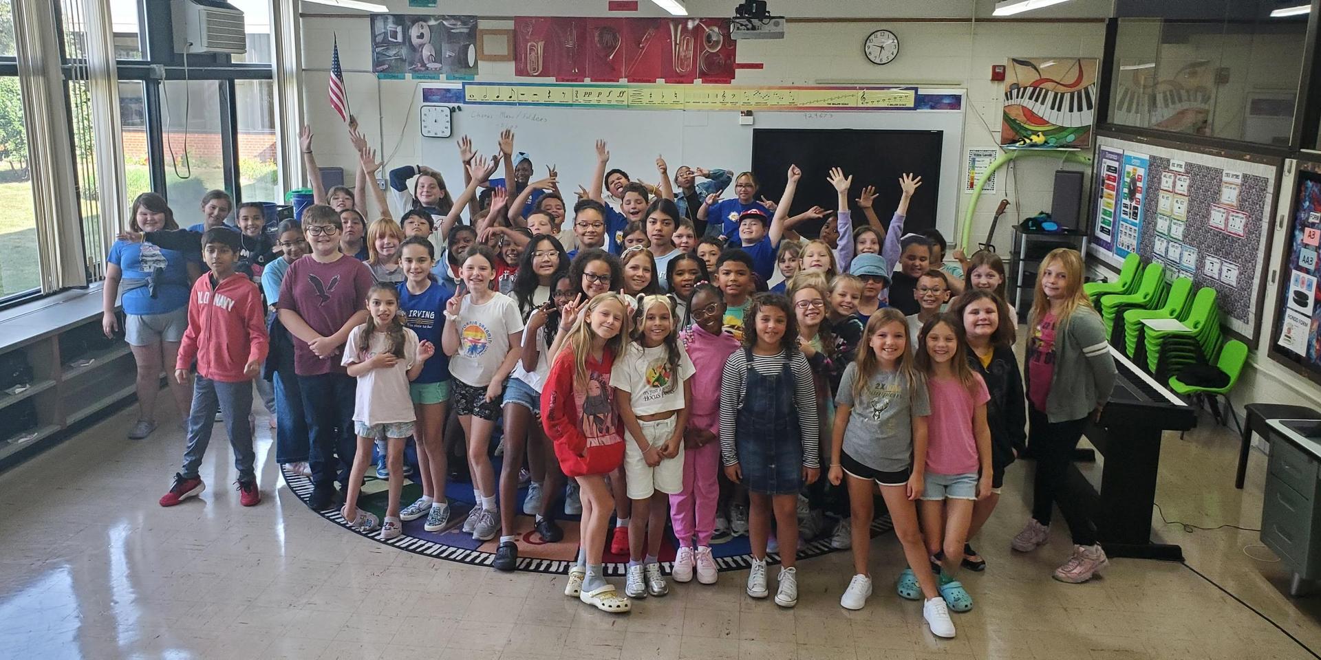 Large group of children smiling and posing in a classroom.