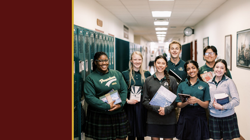 Smiling high school students holding books stand in a hallway
