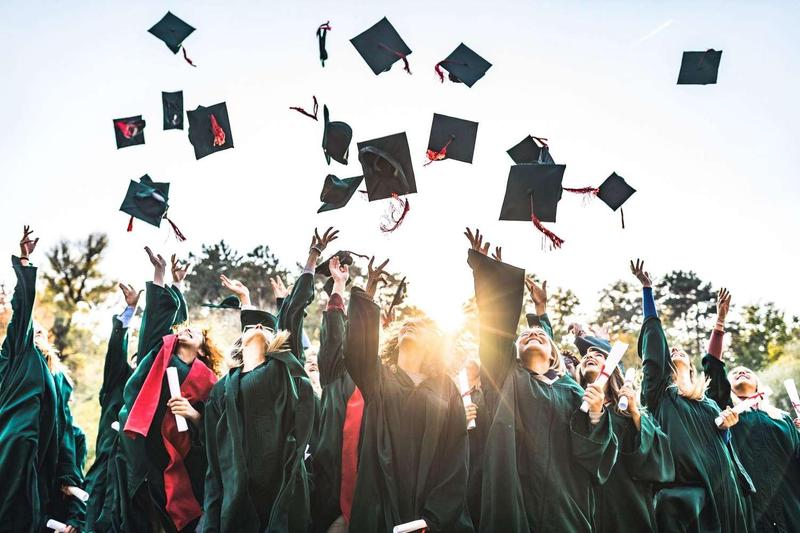 Graduates joyfully tossing their caps into the air in celebration.
