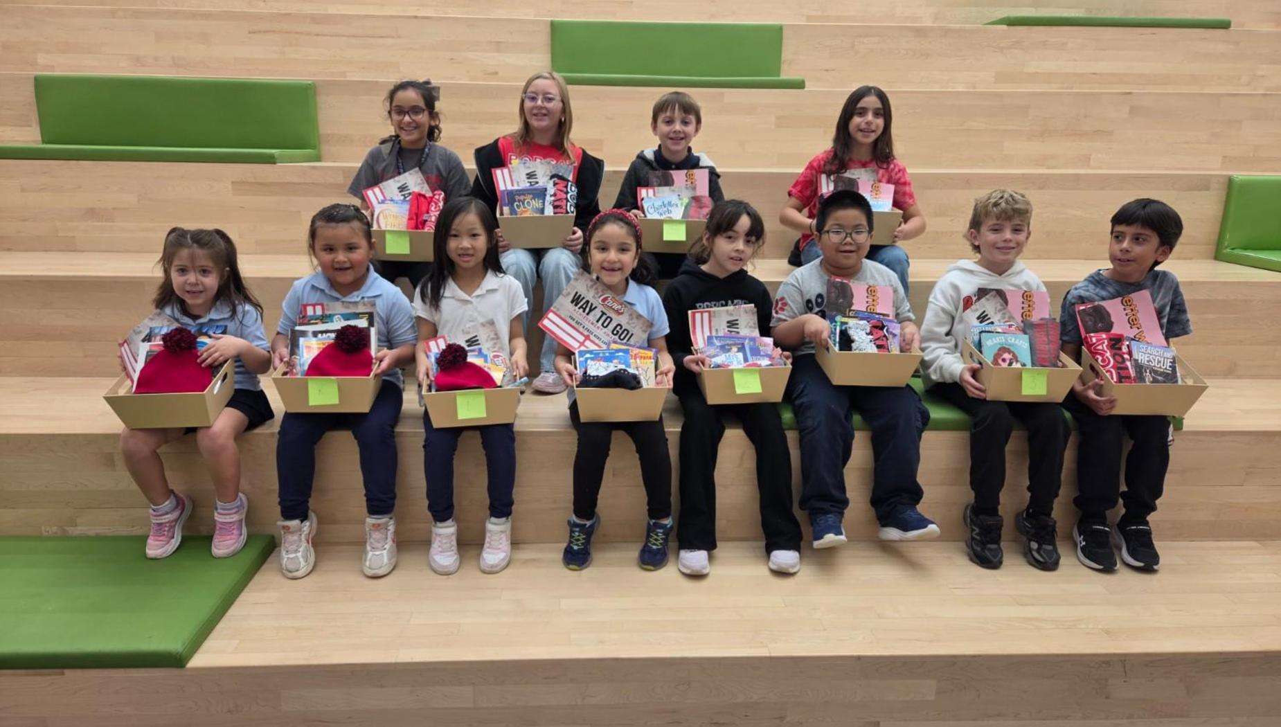 A group of children sitting on steps, holding boxes with crafts and decorations.